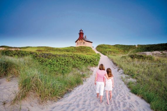 girls walking sandy path to north light